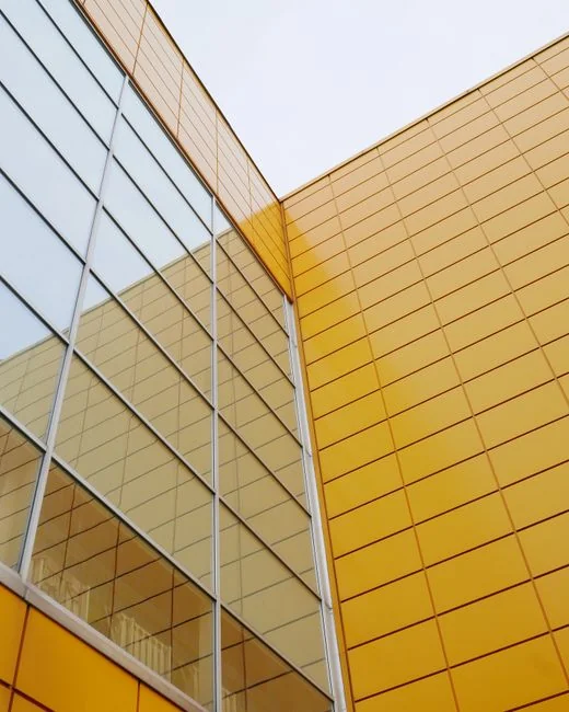Deux ouvriers nettoient les fenêtres d’une façade vitrée moderne à l’aide d’une plateforme suspendue.